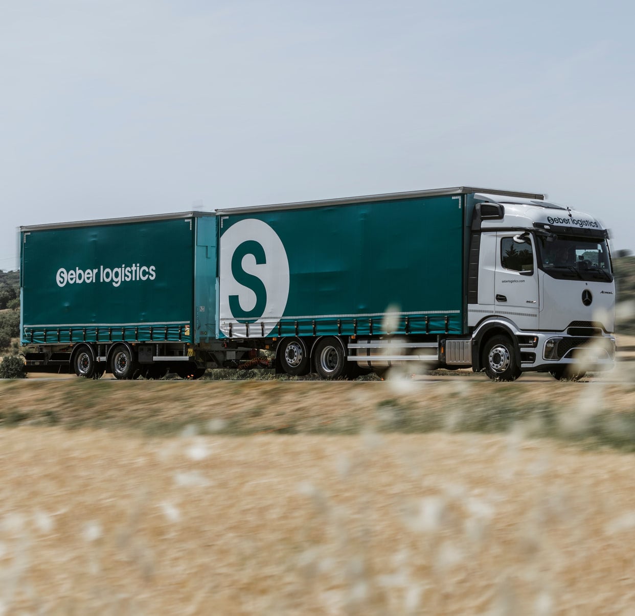 Seber Logístics truck and trailer on a road between fields