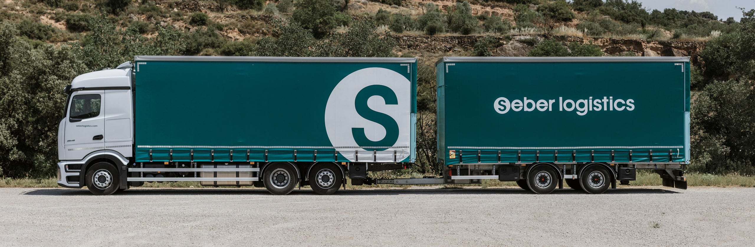 Full side profile of a Seber Logístics road train, from the cab to the rear of the trailer